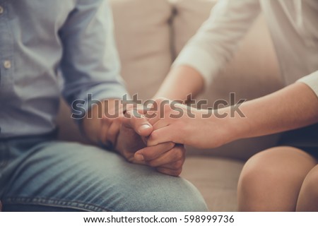 Cropped image of beautiful female psychologist holding her client's hands during the seance Royalty-Free Stock Photo #598999736