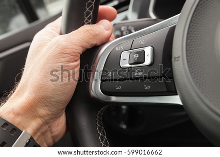 Adaptive cruise control panel buttons on modern car steering wheel, interior details with driver hand Royalty-Free Stock Photo #599016662