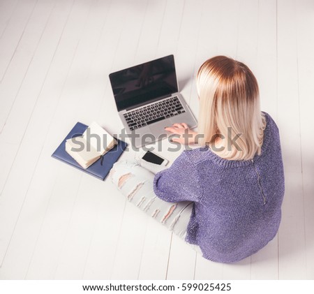 Back view of a woman working behind laptop on the floor