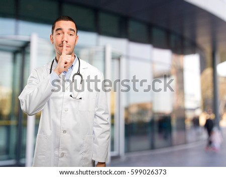 Serious young doctor doing a silence gesture