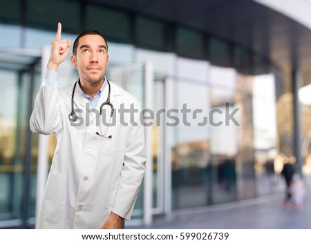 Astonished young doctor pointing up