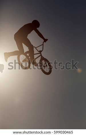 Man riding a bmx bike performing a trick against sunset sky. Extreme sport. 
