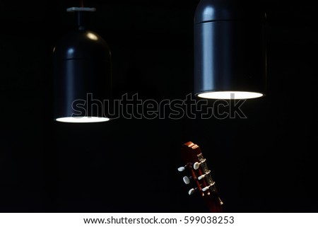 Two ceiling lamps glowing in the dark and a guitar head with tuning keys visible in the foreground