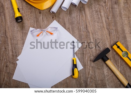 Screwdriver, hammer and helmet. Flashlight, building level and protective glasses. Blank sheet of paper. Architecture plans.