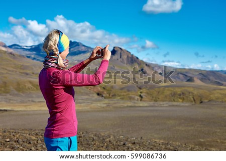 woman hiker photographer taking picture on the mountain background in Iceland