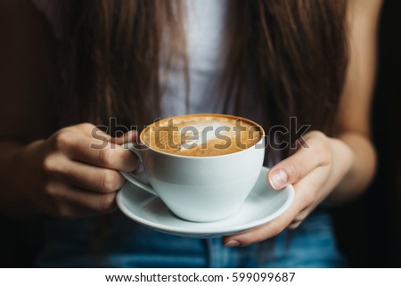 woman relaxing near the window with coffee in hands in a vintage restaurant