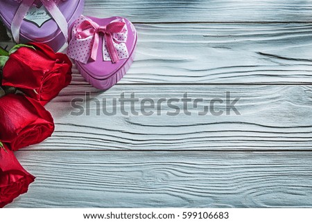 Set of metal heart-shaped present boxes red roses on wooden board celebrations concept.