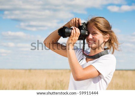 Young girl taking photo against blue sky