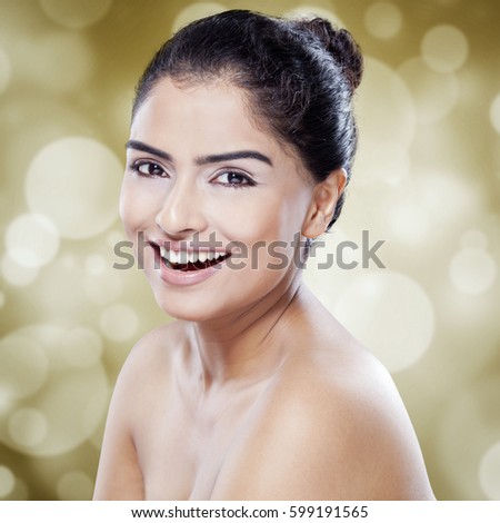 Portrait of pretty woman with black hair and perfect beauty skin smiling at the camera against bokeh background