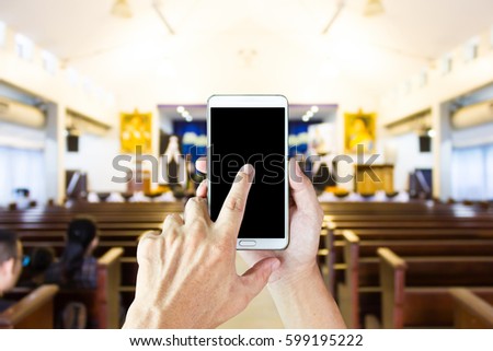 Man use mobile phone, blur image of inside small theater as background.
