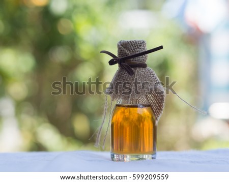 a glass bottle of honey bee from nature pollen flower with hemp sack cloth and brown rope on blurred background Royalty-Free Stock Photo #599209559