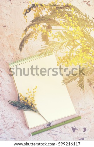 Spring background with mimosa and notepad, toned