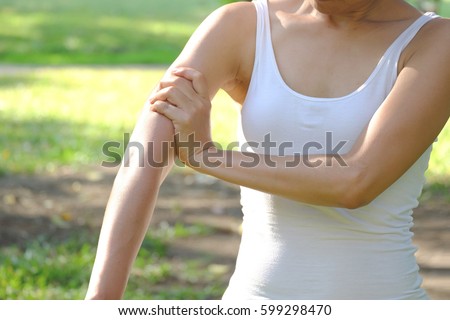 Arms Pain.  Woman Suffering From Painful Feeling In Arm Muscles.in the park. health concept