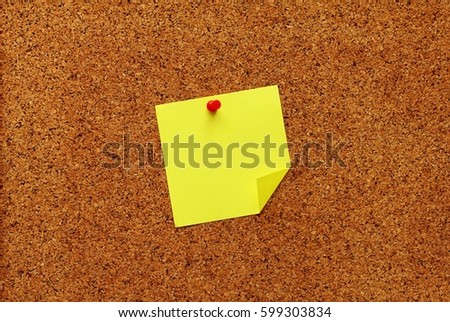 Yellow sticky notes with pin on a cork board