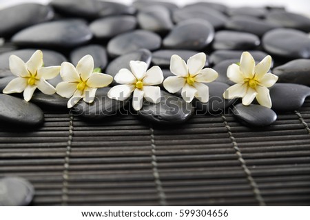 Many of stones with gardenia on bamboo mat