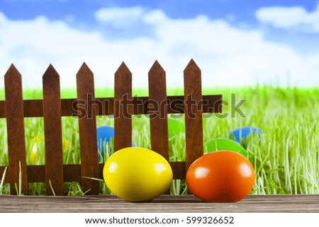 Easter eggs, old wooden fence green grass and blue sky background