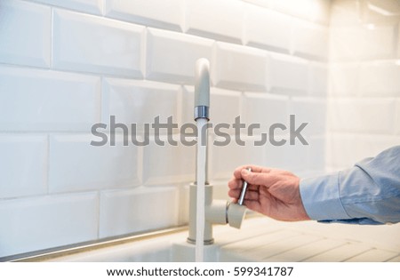 Beige faucet in the kitchen on a background of white tiles 