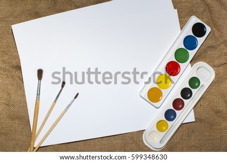 Set of watercolor paints, brushes for painting and blank white paper sheet of sketchbook. mock up, 