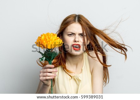 Beautiful girl with a big yellow flower smiling on a light background
