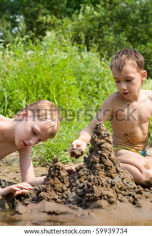 Two children build a sand castle on the river