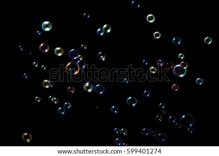 Rainbow soap bubbles on a dark background .
