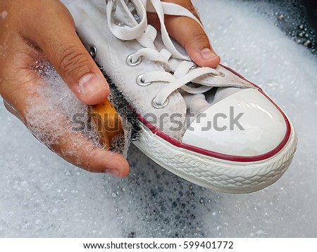Shoes or sneakers in a wash basin with soapy water.washing the dirty sneakers, cleaning the shoes. Royalty-Free Stock Photo #599401772