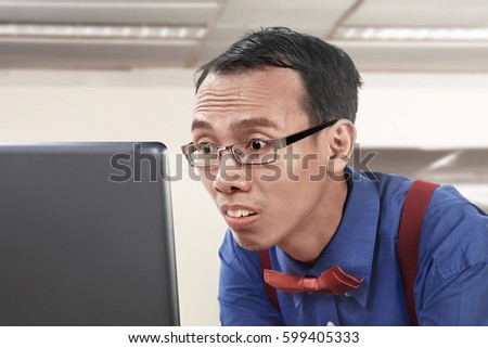 Asian nerdy businessman working using laptop at office