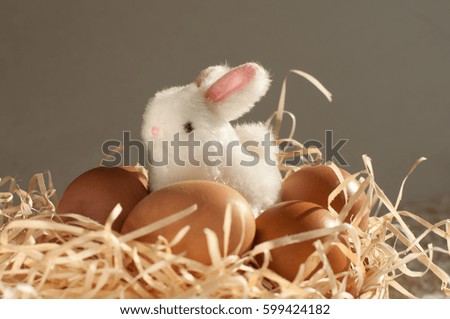 Easter rabbit inside a sieve full of easter eggs on rustic wooden
