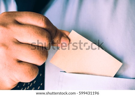 Young man who takes out blank business card from the pocket of his shirt
