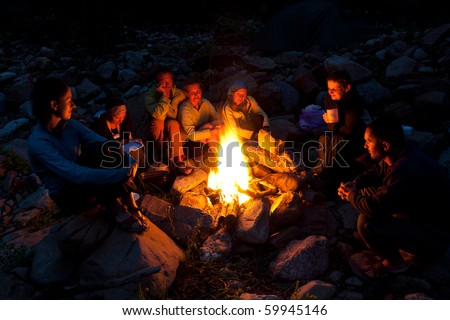 Group of backpackers relaxing near campfire after a hard day, tourist background. Royalty-Free Stock Photo #59945146