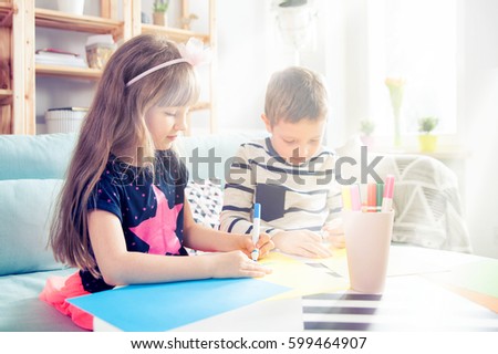 Brother and sister drawing with colorful pencils together at home