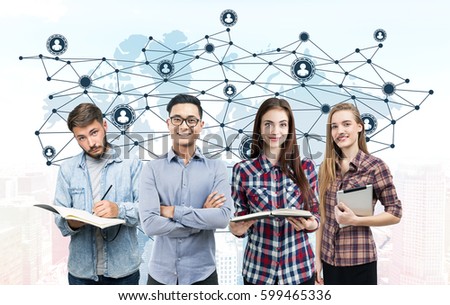 Portrait of a young business team standing with books and a tablet computer near a white wall with a world map and a network sketch drawn on it. Elements of this image furnished by NASA