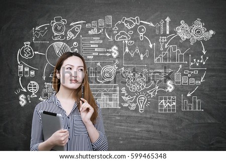 Portrait of an Asian businesswoman holding a tablet and standing near a blackboard with a business scheme drawn on it.