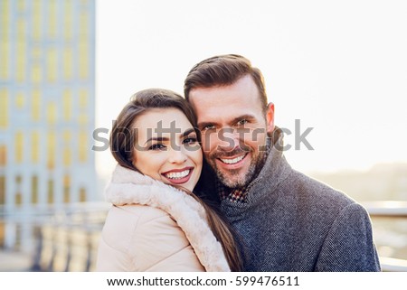 Winter picture of lovely couple standing together in a city, hugging