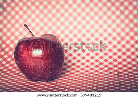 Single, round, juicy apple on a red and white checkered background