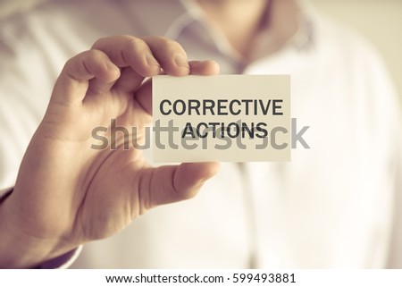 Closeup on businessman holding a card with text CORRECTIVE ACTIONS, business concept image with soft focus background and vintage tone