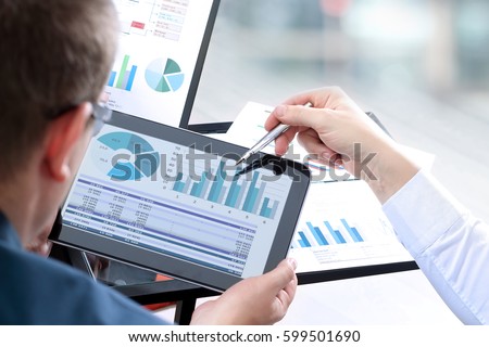 Business colleagues working and analyzing financial figures on a digital tablet Royalty-Free Stock Photo #599501690
