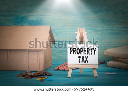 Property Tax. home model, money and a notice board under the sunlit