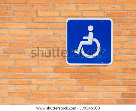Handicap sign with wheelchair on brick wall.