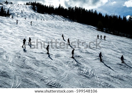 The skiers on the slope during the sunny day. The nice picture of the winter ski atmosphere. Skiers are enjoying the great conditions. 