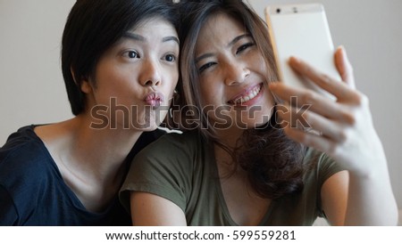 Two mixed race Asian girls taking selfie with smart phone