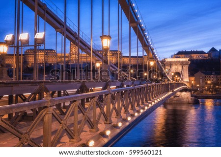 The Chain bridge (Szechenyi lanchid), stunning engineering design in twilight blue sky evening with Castle on background and city lights Royalty-Free Stock Photo #599560121