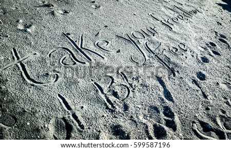 'Take your freedom, and be free' written in sand. Shot in black and white.