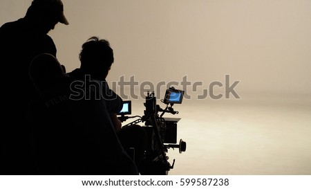 Silhouette of working people or production film crew are making movie or shooting tv on-line content live show in studio with camera equipment set.