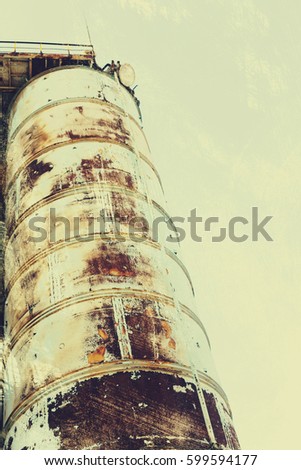Old abandoned concrete plant with iron rusty tanks and metal structures. Crisis, collapse of economy and closure of production facilities led to collapse. Vintage effect, scratches and cracks