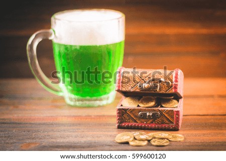 A mug of green beer on the table. Clover leaves. Chest of gold, coins pile. St.Patrick 's Day