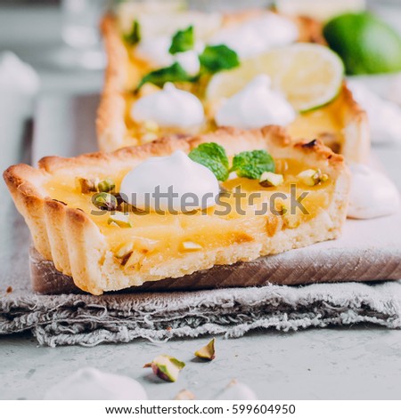 Tart with lime and lemon curd, nut pistachios and meringue on gray table. Homemade Citrus cake. Horizontal image with copy space