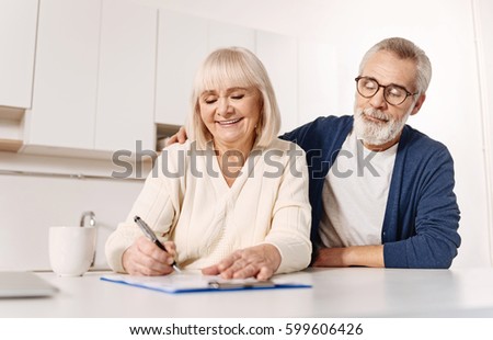 Harmonious aged couple signing documents at home