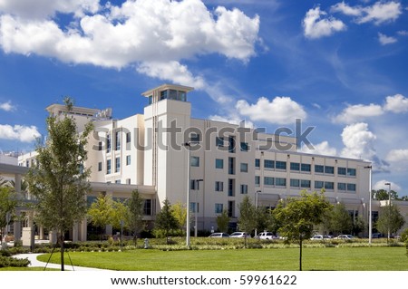 Front entrance to a modern hospital with palm tree landscaping and blue sky