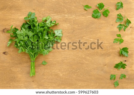 Bunch of parsley on light brown wooden background. Copy-space composition